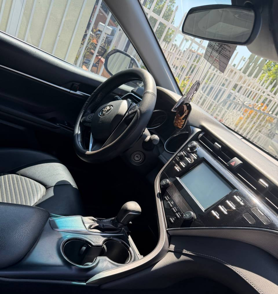 A clean, angled interior shot of a car cabin, showing the black steering wheel, center console, and seats with light gray and black patterned fabric.